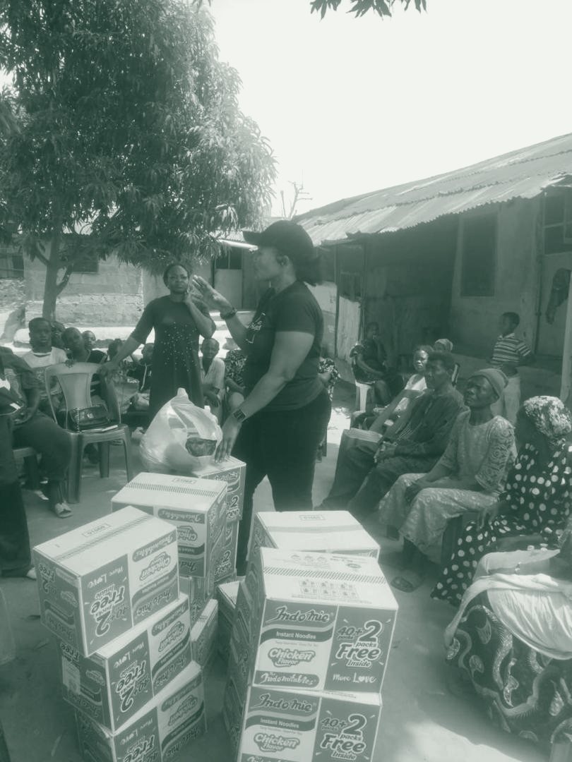 An elderly woman sits with boxes of supplies during a Fisho Initiative visit.